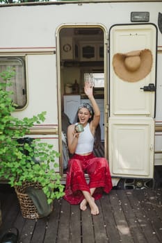 Happy hippie girl are having a good time with cup of tea in camper trailer. Holiday, vacation, trip concept.High quality photo