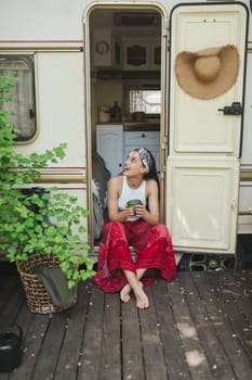 Happy hippie girl are having a good time with cup of tea in camper trailer. Holiday, vacation, trip concept.High quality photo