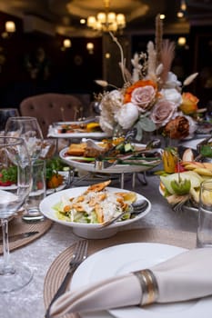 decorated table with white dishes and napkins with various dishes. festive table in the restaurant.