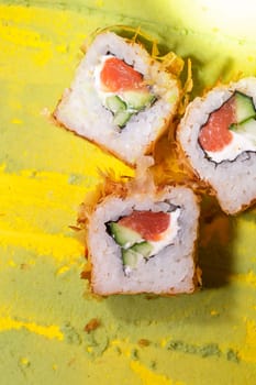 japanese cuisine rolls with fish, cucumber and cheese on a yellow background.