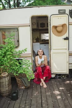 Happy hippie girl are having a good time with cup of tea in camper trailer. Holiday, vacation, trip concept.High quality photo