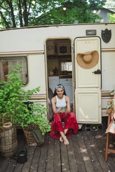 Happy hippie girl are having a good time with cup of tea in camper trailer. Holiday, vacation, trip concept.High quality photo