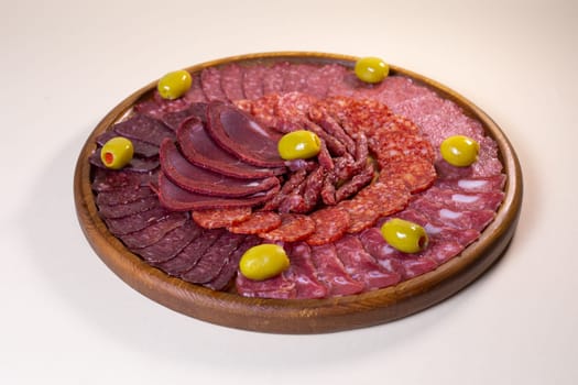 cold cuts of sausage delicacies on a wooden round stand.