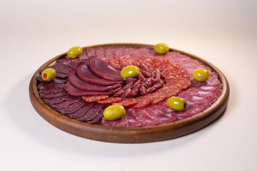 cold cuts of sausage delicacies on a wooden round stand.