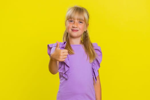 Like. Happy young preteen child girl kid looking approvingly at camera showing thumbs up, like sign positive something good, positive feedback great news. Children isolated on studio yellow background