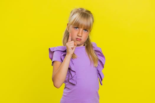 Quarrel. Displeased young cute blonde school girl gesturing hands with irritation and displeasure, blaming scolding for failure, asking why this happened. Preteen female child kid on yellow background
