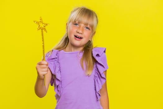 Magician school girl witch gesturing with magic wand fairy stick, making wish come true, casting magician spell, advertising holidays sale discount. Child kid isolated on studio yellow background