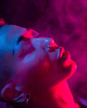 Asian woman with short haircut smoking in neon light. close-up portrait