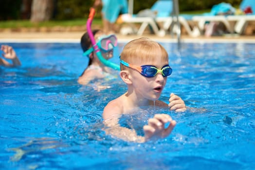 Young boy kid child eight years old splashing in swimming pool having fun leisure activity. Boy happy swimming in a pool. Activities on the pool, children swimming and playing in water, happiness and summertime