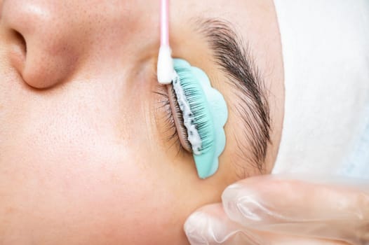 The master removes the composition for lamination from the client's eyelashes with a cotton swab. Eyelash perm procedure