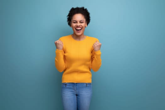 cheerful young 25 year old hispanic lady with afro tail in studio background with copy space.