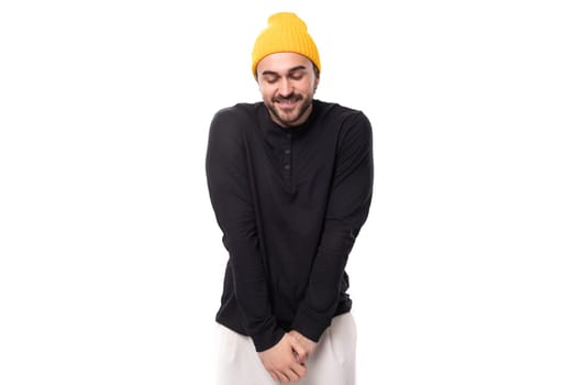 young modest brutal male model dressed in a black jacket and a yellow hat.