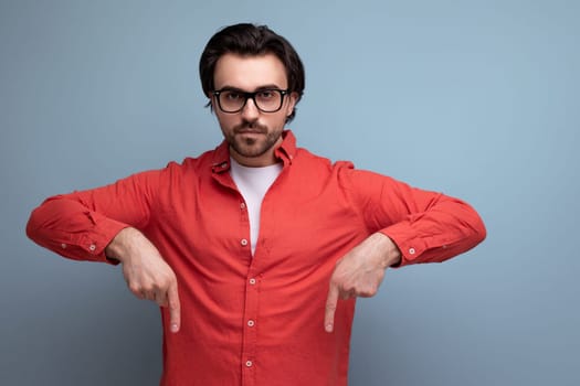 handsome caucasian brunette 30s male manager in a red shirt reports a promotional offer hanging on the wall.