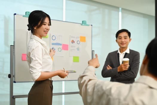 Smiling Asian female manager explaining information, talking about company strategy and business plan during meeting.