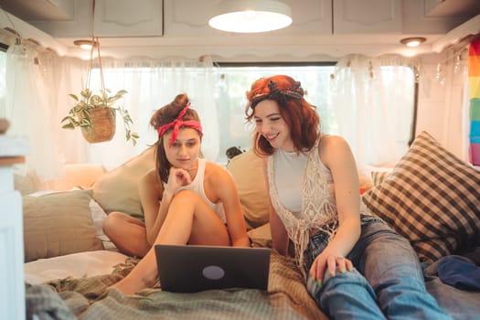 Portrait of a cute lesbian couple. Two girls spend time tenderly together watching movie on laptop in a camper trailer. Love and attitude. LGBT concept. High quality photo