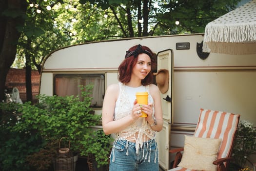 Happy hippie girl are having a good time with cup of tea in a camper trailer. Holiday, vacation, trip concept.High quality photo