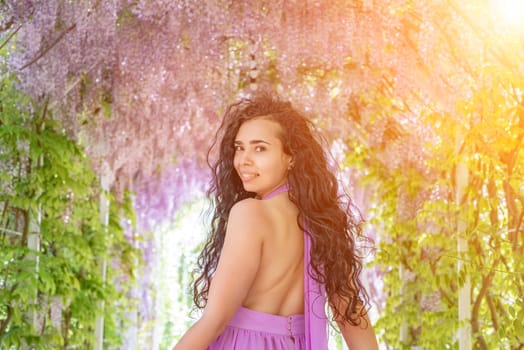 Woman wisteria lilac dress. Thoughtful happy mature woman in purple dress surrounded by chinese wisteria.