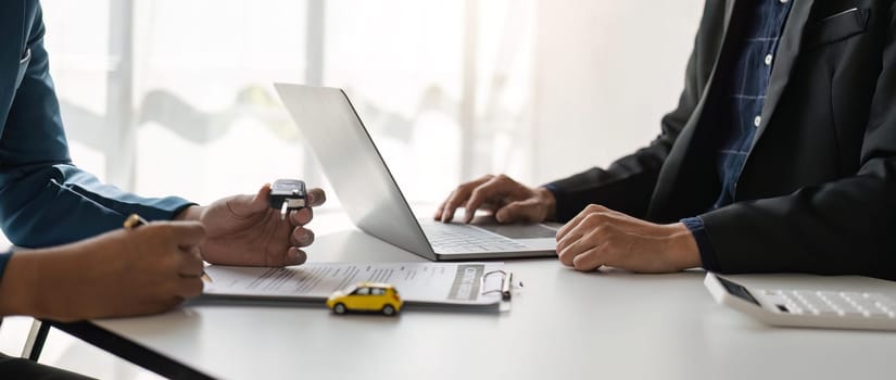 signing car insurance document or lease paper. Writing signature on contract or agreement. Buying or selling new or used vehicle. Car keys on table. Warranty or guarantee. Customer or salesman.