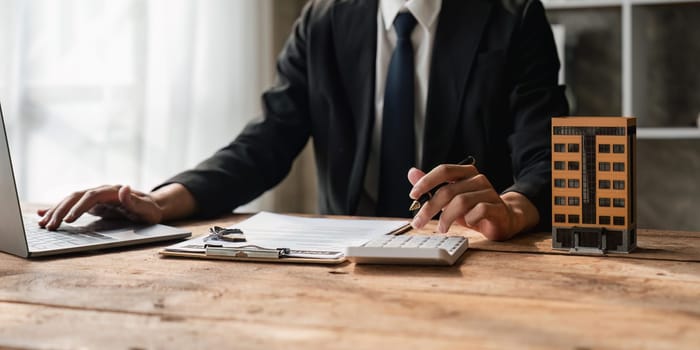 Real estate agent working with laptop at table in office.