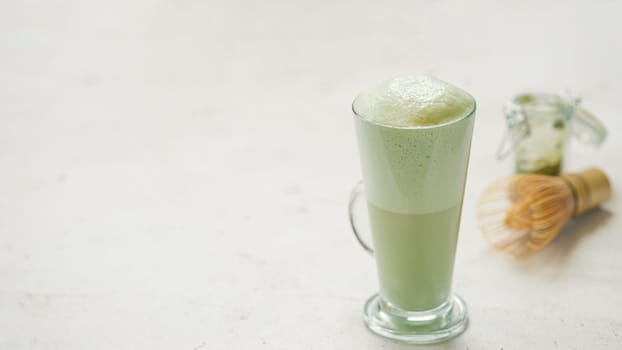 Matcha green tea latte in glass. Matcha latte on light background. Copy space. Banner