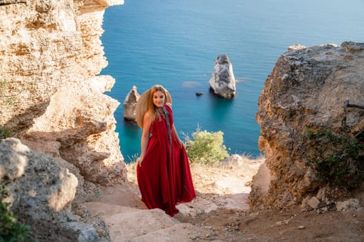 A woman in a red flying dress fluttering in the wind, against the backdrop of the sea