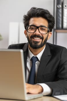 Close-up portrait indian bearded businessman face freelancer at home office workplace working on laptop computer. Manager freelancer indian man works on notebook send messages makes online purchases