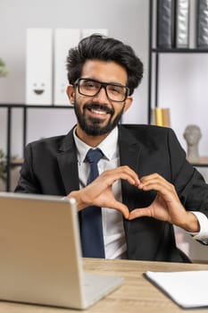 I love you. Indian business man makes symbol of love, showing heart sign to camera, express romantic feelings, express sincere positive feelings at home office workplace. Charity, gratitude, donation