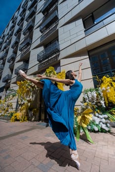 Beautiful Asian ballerina posing against the backdrop of a building decorated with flowers