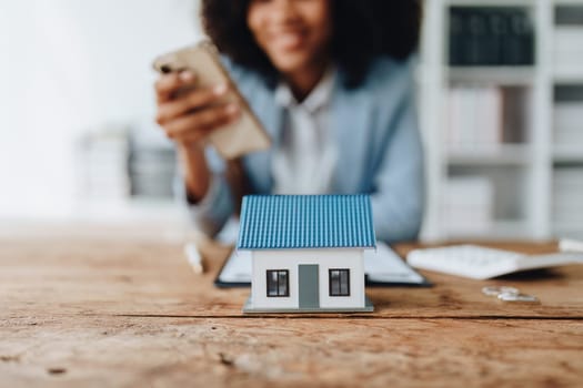 Real estate agent, African American businesswoman Africans use smartphone and calculators to offer mortgages to their clients. Home mortgage and insurance finance concepts.