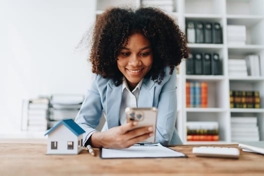 Real estate agent, African American businesswoman Africans use smartphone and calculators to offer mortgages to their clients. Home mortgage and insurance finance concepts.