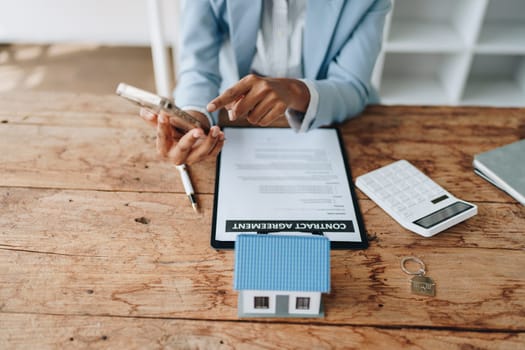 Real estate agent, African American businesswoman Africans use smartphone and calculators to offer mortgages to their clients. Home mortgage and insurance finance concepts.