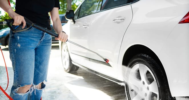 Girl washing a car weels in a self-service car wash station. Wash car self-service station.