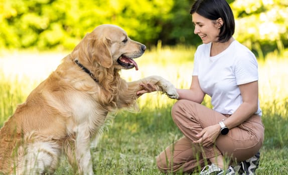 Girl training golden retriever dog outdoors