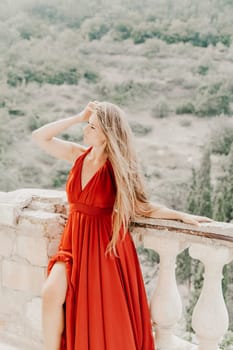 Woman red dress. Summer lifestyle of a happy woman posing near a fence with balusters over the sea