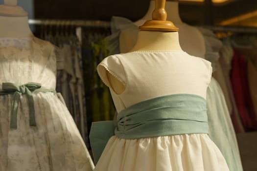 Showcase behind glass with formal children's dresses in a children's clothing store.