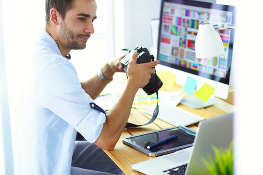 Portrait of young designer sitting at graphic studio in front of laptop and computer while working online