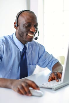 African american businessman on headset working on his laptop.