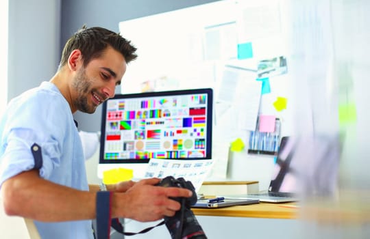 Portrait of young designer sitting at graphic studio in front of laptop and computer while working online