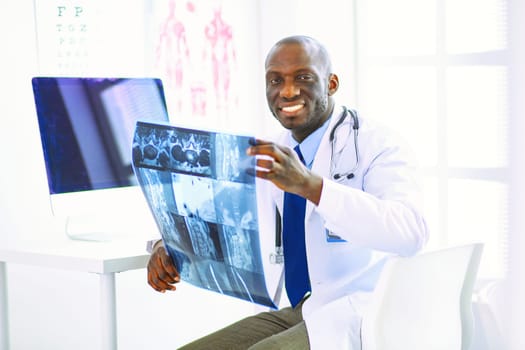 Portrait young african medical doctor holding patient's x-ray.