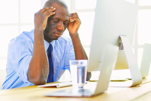 African american businessman on headset working on his laptop.