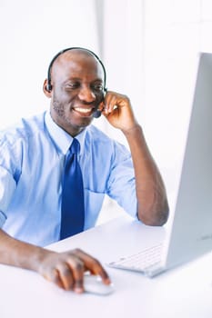 African american businessman on headset working on his laptop.