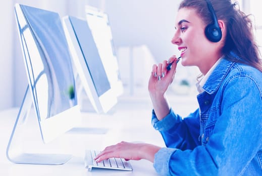 Smiling businesswoman with headset using laptop at the desk in work