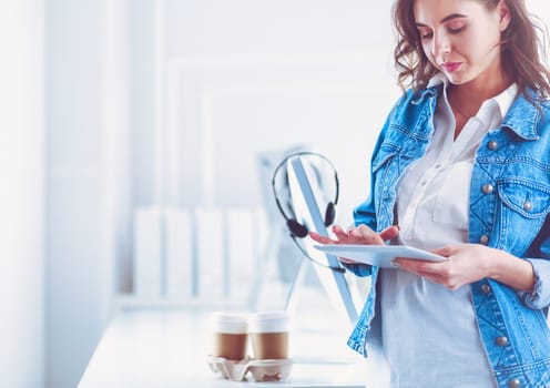 Smiling woman drinking coffee and using tablet in the cafe