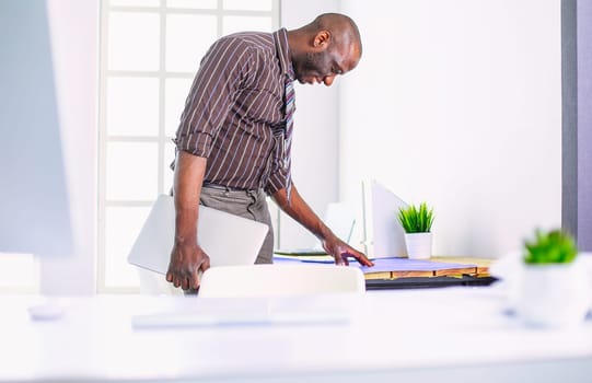 African american architect working with computer and blueprints in office.