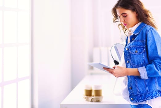 Smiling woman drinking coffee and using tablet in the cafe