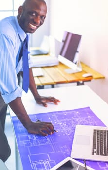 African american architect working with computer and blueprints in office.