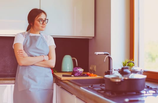Woman cooking in new kitchen making healthy food with vegetables.