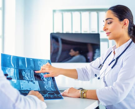 Two doctors studying x-ray image, consulting in bright office.