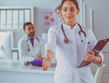 Portrait of young beautiful woman doctor giving handshake.
