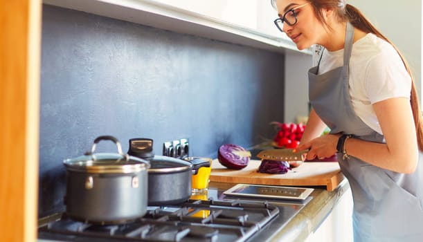 Young woman using a tablet computer to cook in her kitchen.